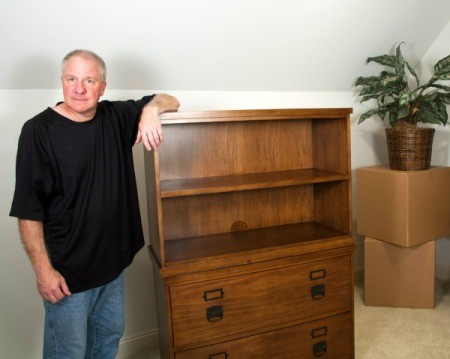 Man standing next to heavy hutch and boxes on carpet