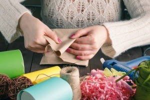 Woman hands folding paper surrounded by various craft supplies