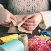 Woman hands folding paper surrounded by various craft supplies