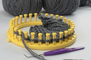 Yellow Knifty Knitter Loom with partial weaving made with grey yarn