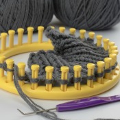 Yellow Knifty Knitter Loom with partial weaving made with grey yarn