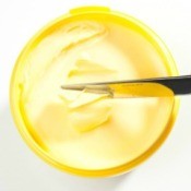 Hand using Knife to remove margarine from tub