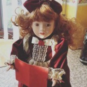 red haired doll in maroon dress holding a book