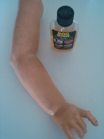 A doll arm with a bottle of Goo Gone