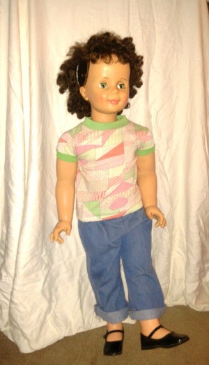 A cleaned up brown haired doll dressed in blue jeans.