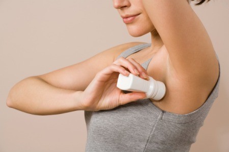 Woman in tank top applying deodorant