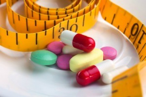 Variety of pills and tape measure on a white background