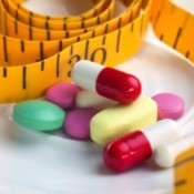 Variety of pills and tape measure on a white background