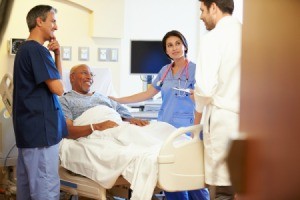 Smiling man in hospital bed surrounded by 3 doctors