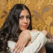 Young girl in sweater dress hugging her knees