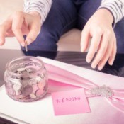 Placing money in a jar labelled wedding on top of a wedding album