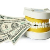 Dental mold biting down on several large note dollar bills