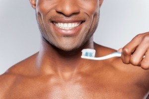 Close up of a man with a bright white smile holding a toothbrush