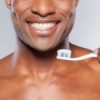 Close up of a man with a bright white smile holding a toothbrush