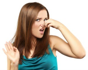 Woman with disgusted expression holding her nose and holding her other hand up in front of her