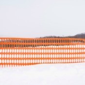 Bright Orange plastic mesh snow fence in a field of snow