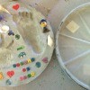 Using Flower Pot Saucers for Stepping Stones - Finished stepping stone with small toys around the hand and foot print.