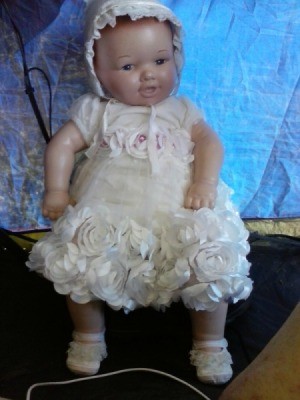 baby doll wearing white dress and bonnet