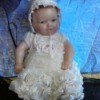 baby doll wearing white dress and bonnet