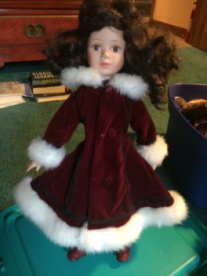 dark haired doll wearing a dark maroon coat with white fur collar and cuffs