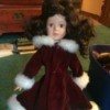 dark haired doll wearing a dark maroon coat with white fur collar and cuffs