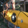 A kayak being hung on the side of a chicken coop.