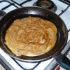 A banana crepe being cooked in a skillet.