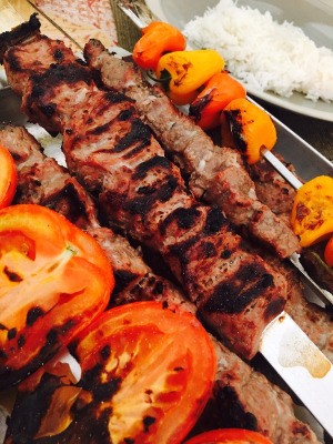A skewer of Persian Lamb Kabobs with roasted vegetables.