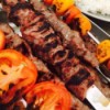 A skewer of Persian Lamb Kabobs with roasted vegetables.