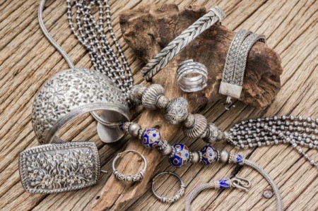A pile of silver jewelry on a wooden surface.