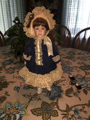 doll wearing blue coat with lace trim and matching hat