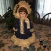 doll wearing blue coat with lace trim and matching hat