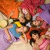 Group of girls in sleeping bags in a circle with heads together