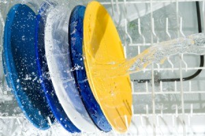 Brightly colored plates being sprayed by water in dishwasher