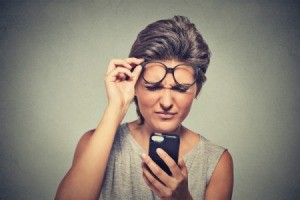 Woman looking at cell phone with confused expression