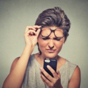Woman looking at cell phone with confused expression