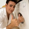 Man giving two thumbs up in front of clothes dryer