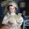 doll wearing fancy off white dress with matching hat