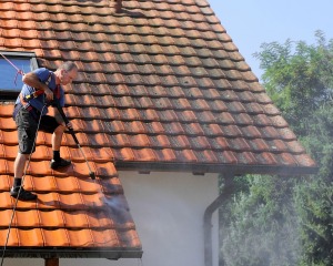 Man power washing tile roof