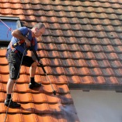 Man power washing tile roof