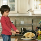 Young boy making crepes on the stove