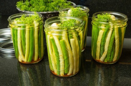 Several jars of yellow and green beans with spices ready to be processed