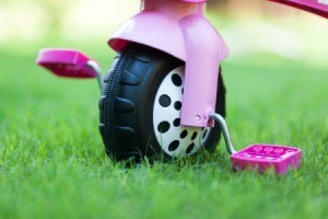 Close up of the front wheel of a pink toddler trike