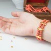 Elastic Beaded Bracelet on a girls wrist near string of matching beads and small gold beads loose on counter