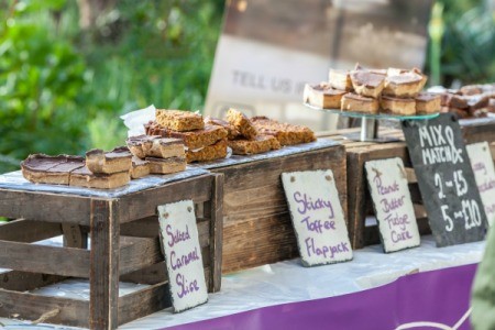 Plates of baked goods on crates with cards in front listing names and prices