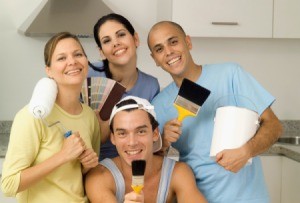 Group of people holding painting supplies and samples in a white kitchen
