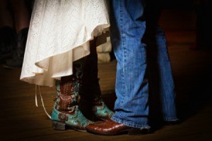 Feet and legs of groom in cowboy boots and bluejeans and bride in wedding dress and boots