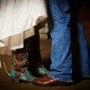 Feet and legs of groom in cowboy boots and bluejeans and bride in wedding dress and boots