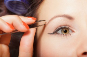 Close up of woman with thin eyebrows plucking them