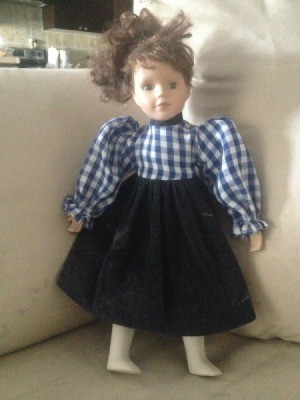 doll wearing a dress with blue and white checkered top and dark skirt